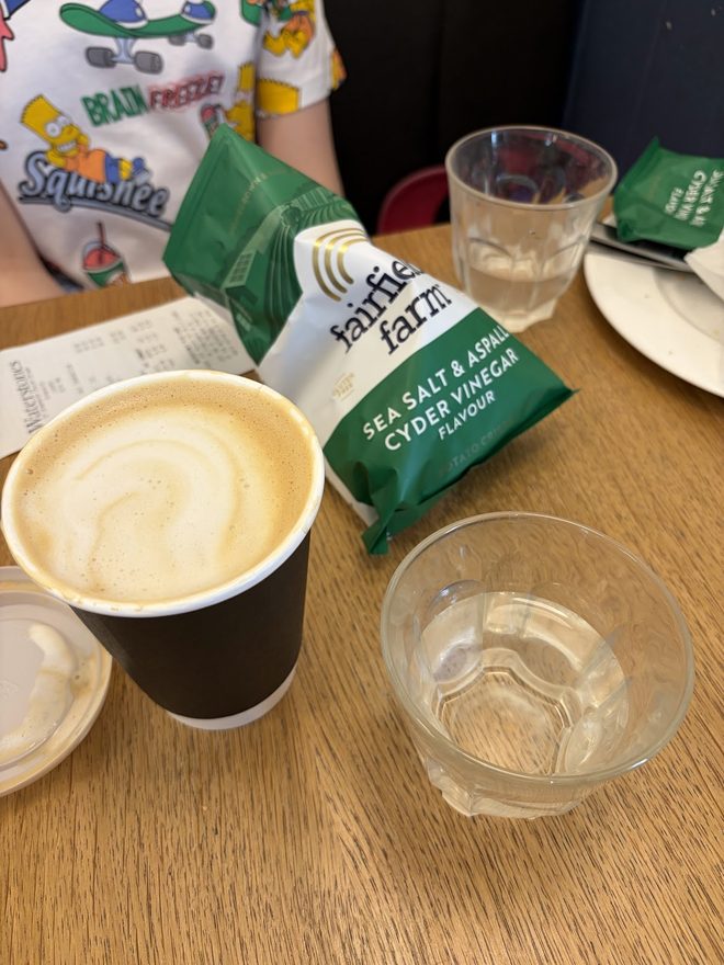 A takeaway latte on a busy table in the café